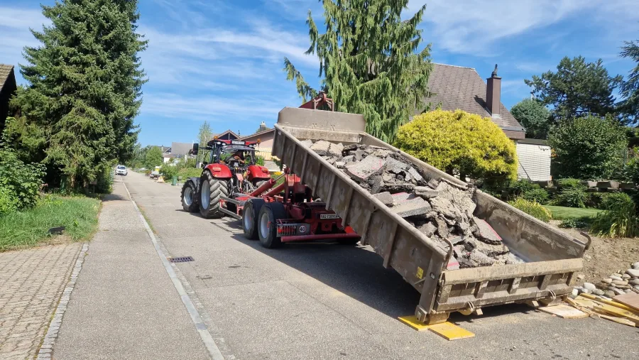 Traktor mit Anhänger voller Bauschutt beim Abtransport