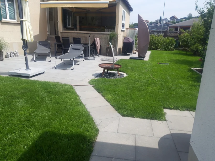 Gepflegter Garten mit Rasen, Plattenweg und Sitzplatz, angelegt von T.Lerch